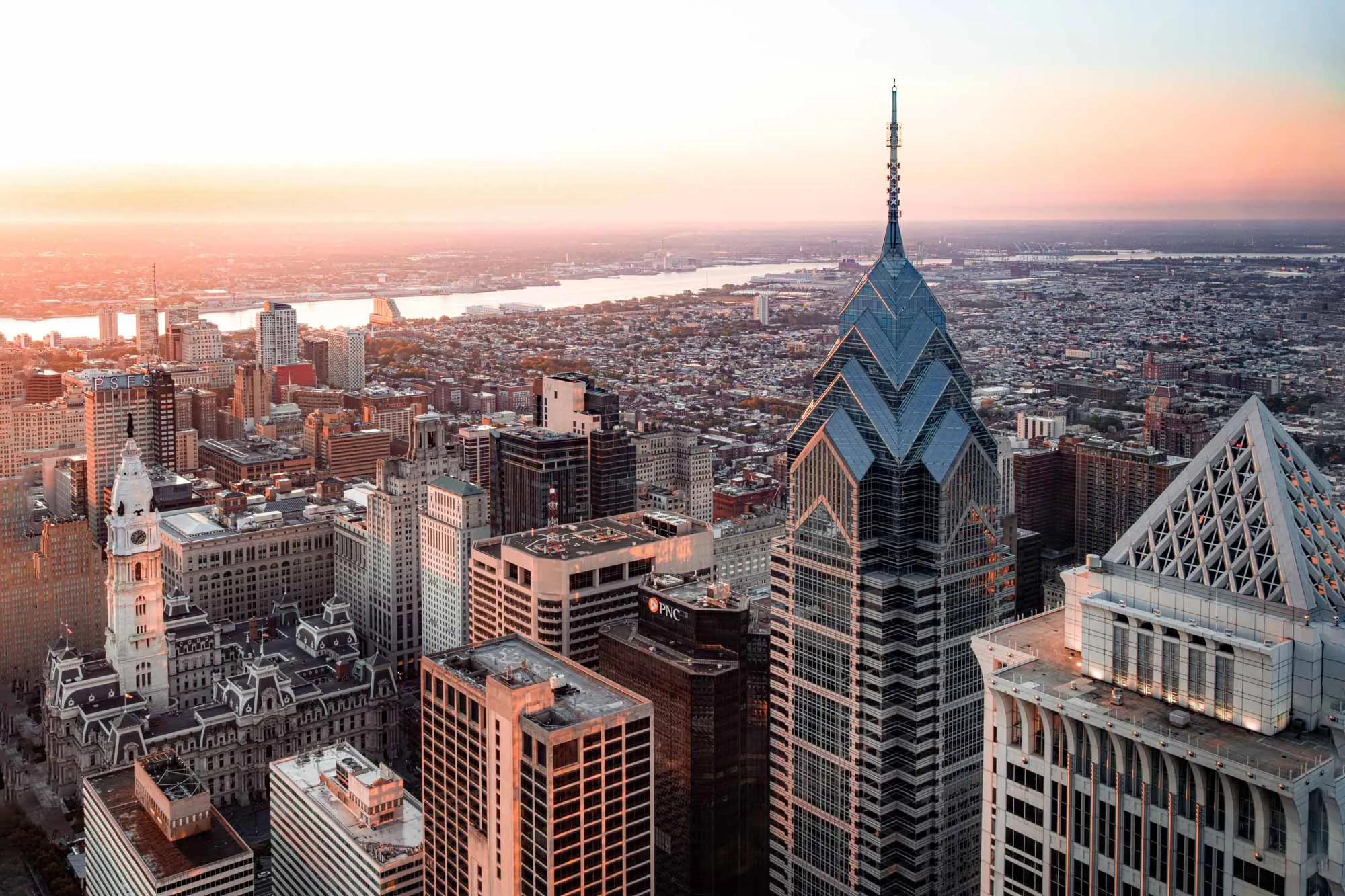 Sunset view from the Empire State Building, highlighting a stunning skyline with colorful clouds and city lights beginning to twinkle.
